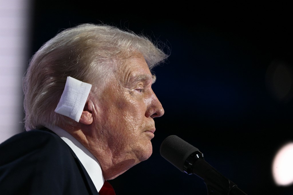 US former President and 2024 Republican presidential candidate Donald Trump, a bandage on his ear after he was injured during an assassination attempt, speaks onstage during the last day of the 2024 Republican National Convention at the Fiserv Forum in Milwaukee, Wisconsin, on July 18, 2024. Donald Trump will get a hero's welcome Thursday as he accepts the Republican Party's nomination to run for US president in a speech capping a convention dominated by the recent attempt on his life. (Photo by Brendan SMIALOWSKI / AFP)